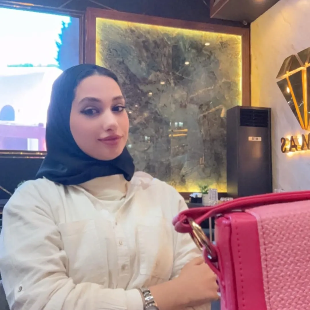 Image of 𝓜𝓪𝓻𝓲𝓪𝓶 𝓪𝓵 💕 from Instagram black hijab, white shirt, silver watch, pink bag, indoor setting