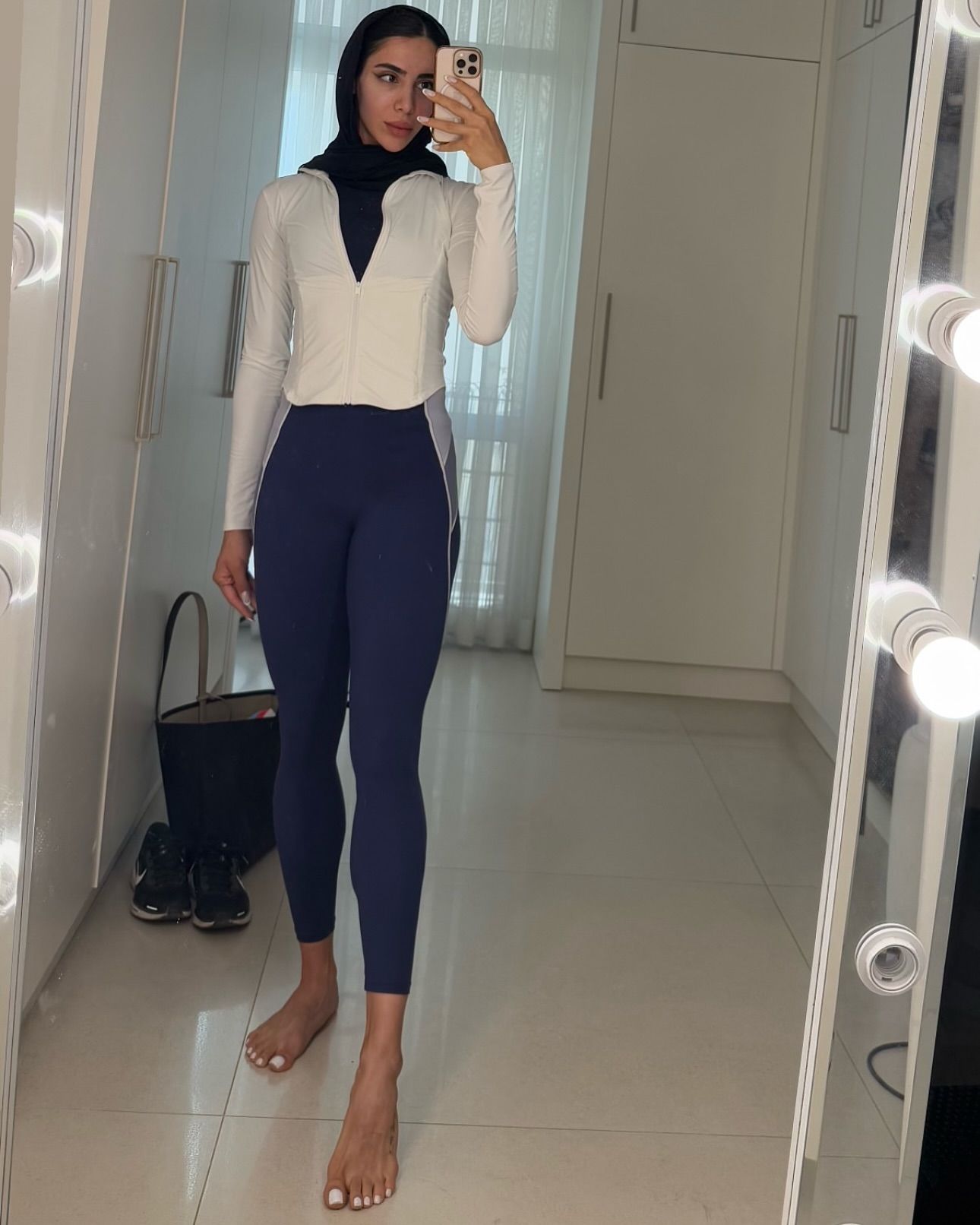 Image of honarmandaniraniziba from Instagram white jacket, black scarf, navy leggings, barefoot, mirror selfie, wardrobe background