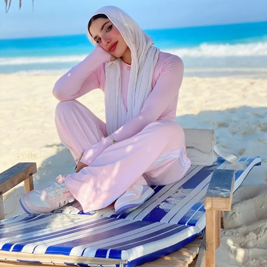 Image of Yasmin Samir from Instagram pink outfit, white scarf, sneakers, beach, striped lounger