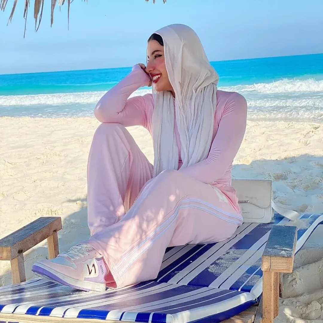 Image of Yasmin Samir from Instagram pink outfit, hijab, sneakers, beach, striped lounge chair