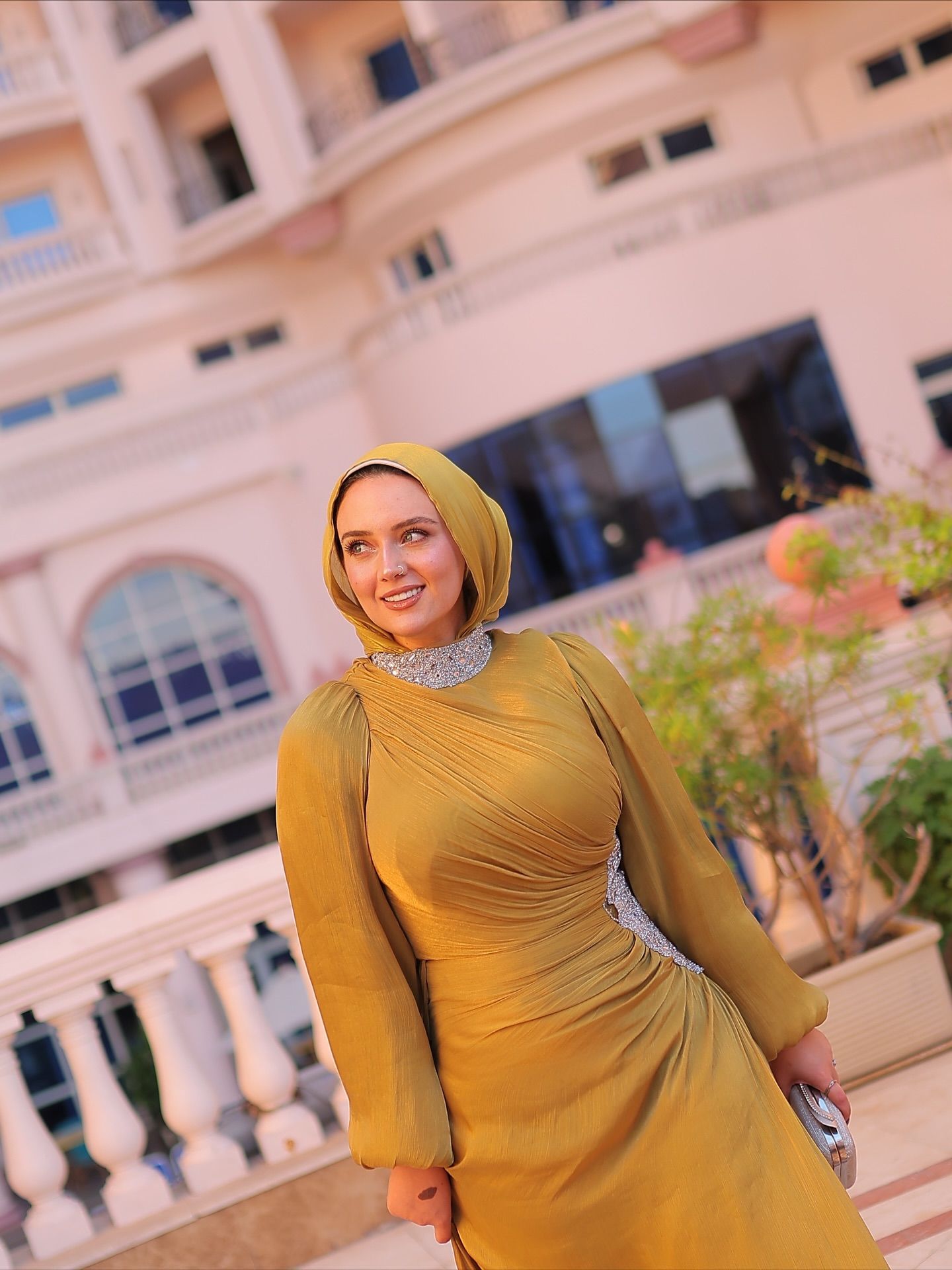 Image of ميرنا عبدالوهاب from Instagram yellow dress, hijab, long sleeves, silver clutch, urban setting