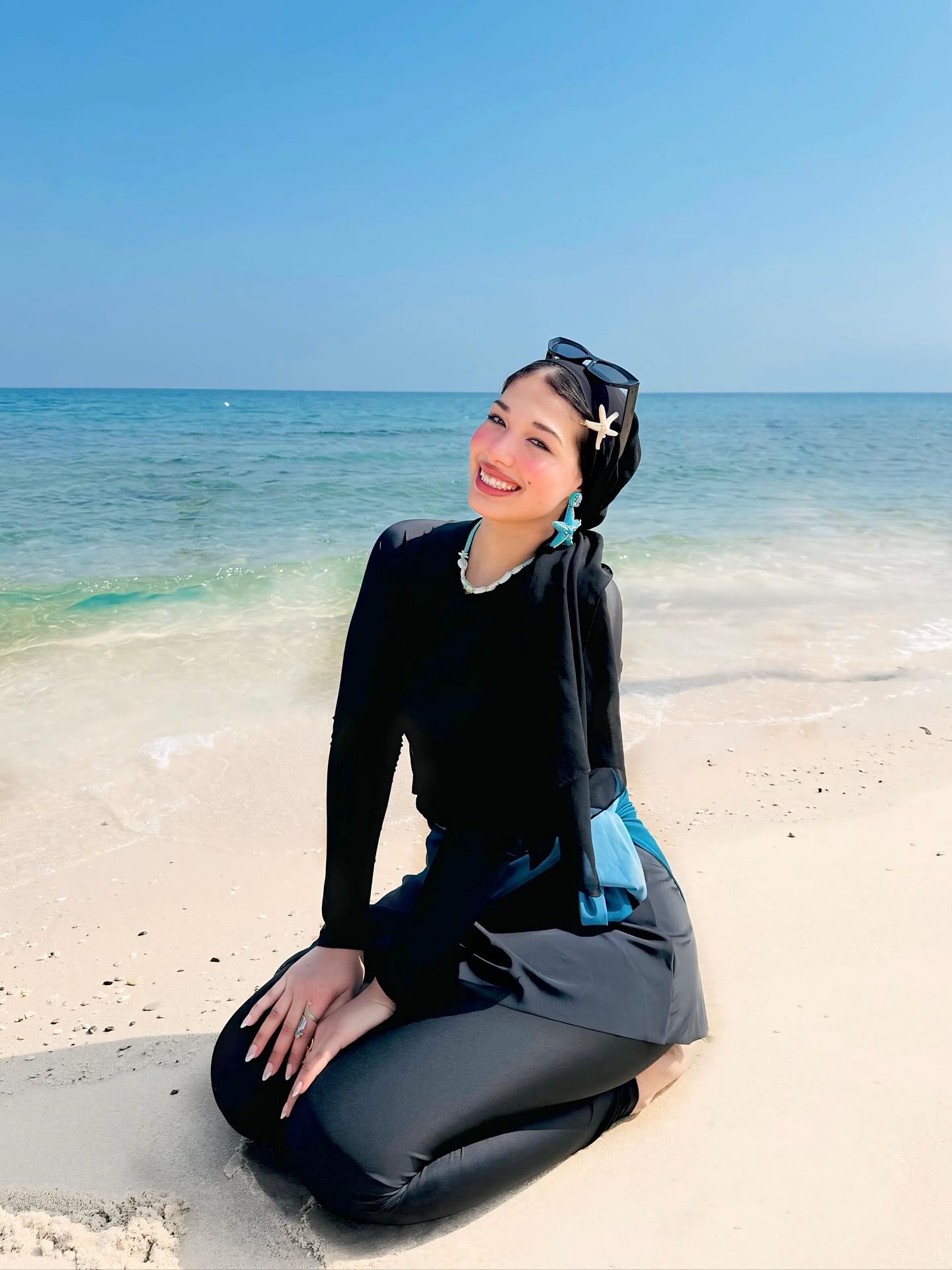 Image of ﮼عائشه ﮼ from Instagram headscarf, beach, black outfit, starfish accessories, sunglasses, necklace, earrings, barefoot