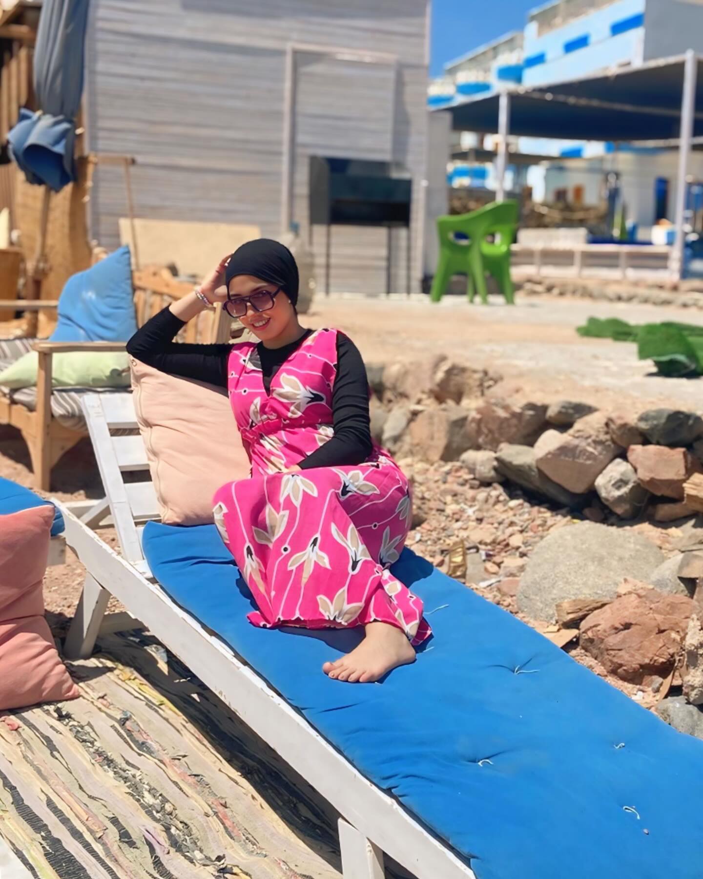 Image of NaDa NabiL-ندي نبيل from Instagram pink dress, floral pattern, black top, sunglasses, bracelet, beach, lounge chair, barefoot