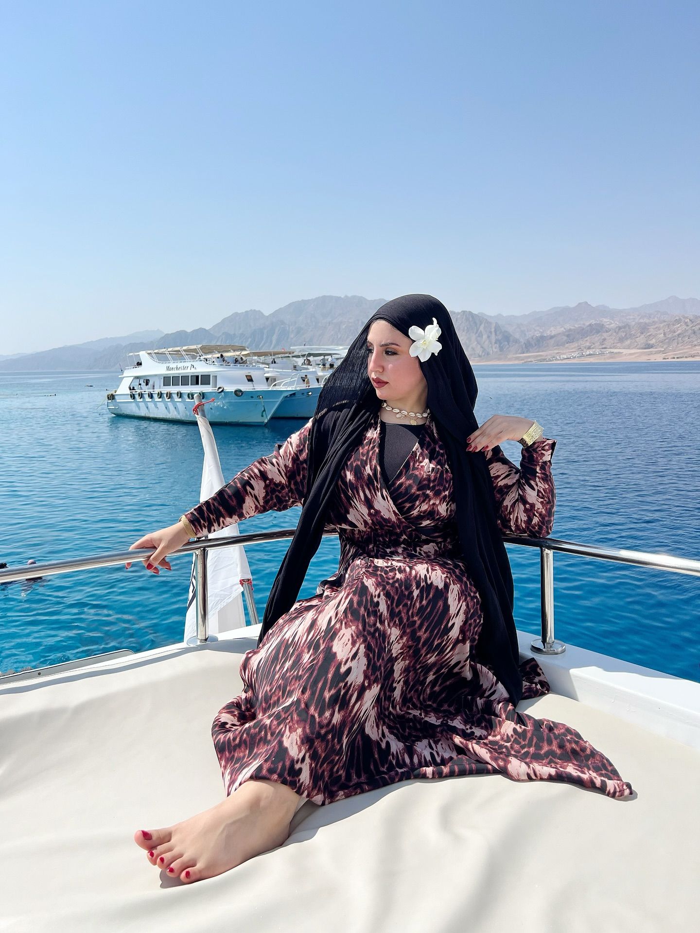 Image of Aya Ezzat from Instagram boat, ocean, scenic background, maxi dress, hijab, floral accessory, choker, barefoot, bracelet, elegant, fashionable