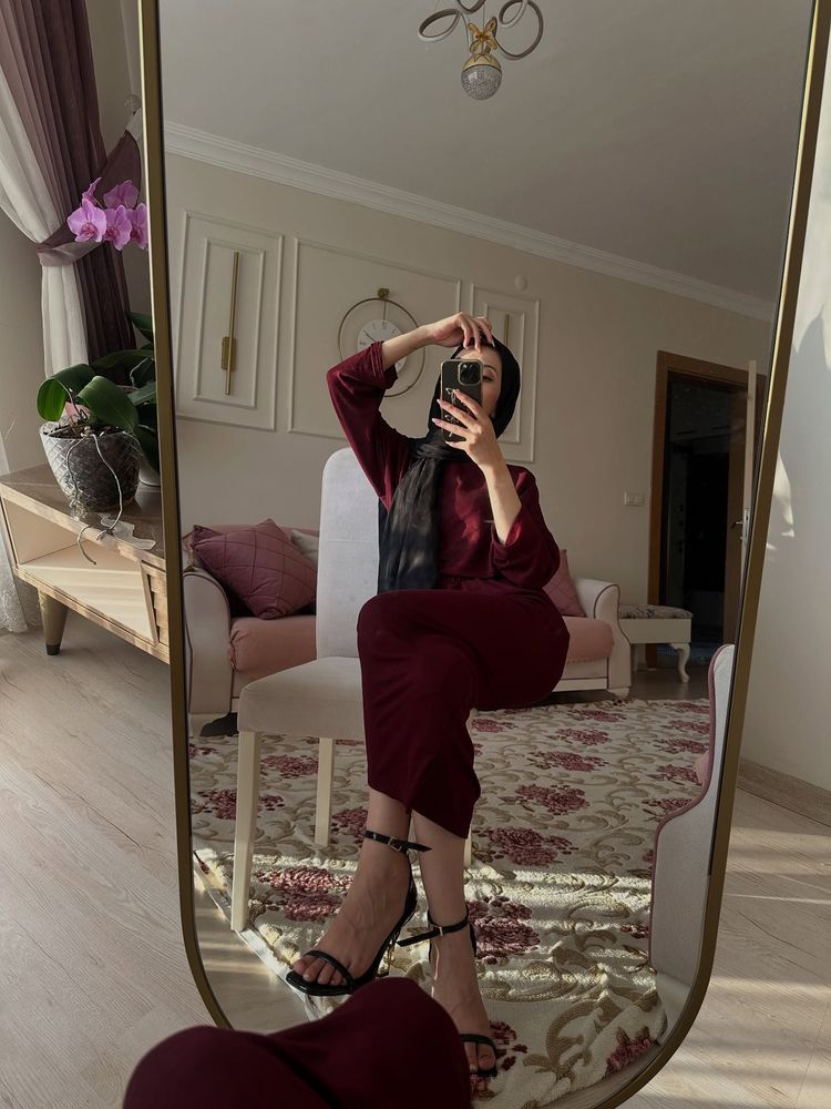 Woman in burgundy outfit and black strappy heels in a stylish room.