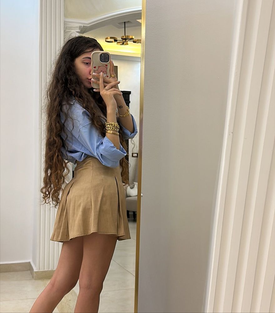 Girl in light blue shirt and tan skater skirt in a bright setting
