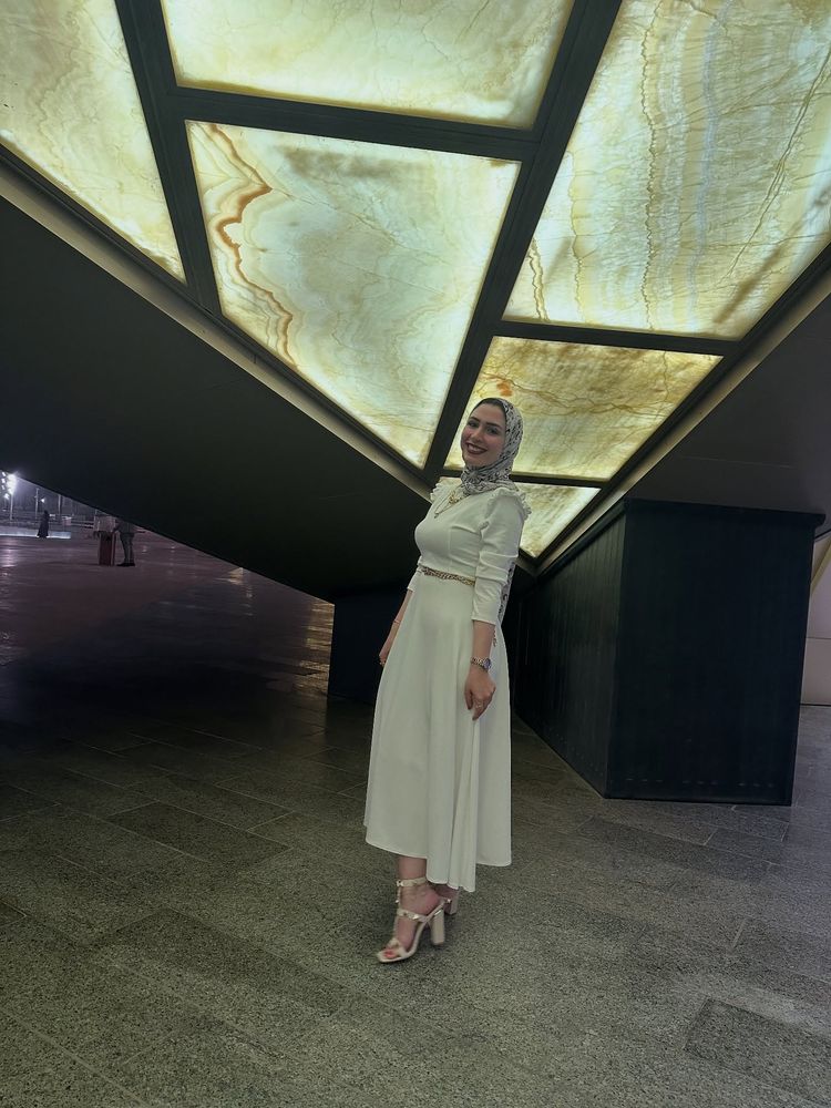 Woman in an elegant white dress and strappy heels against modern architecture.