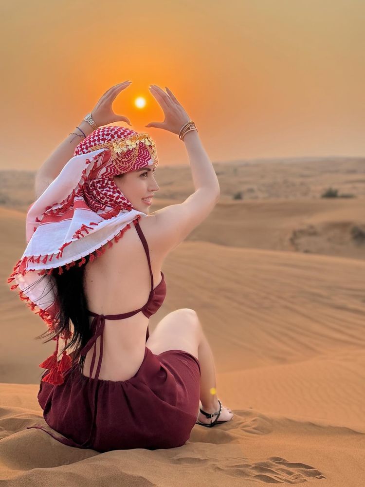 Girl in maroon top and sandals holding sun in desert setting