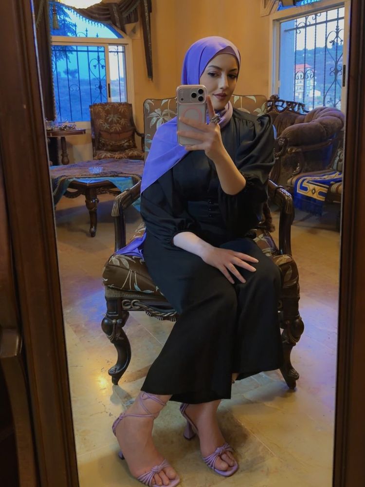 Girl in black dress and lavender strappy sandals in a cozy room