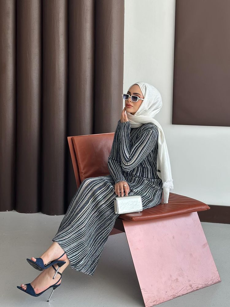 Woman in striped dress and high heels sitting in a modern setting