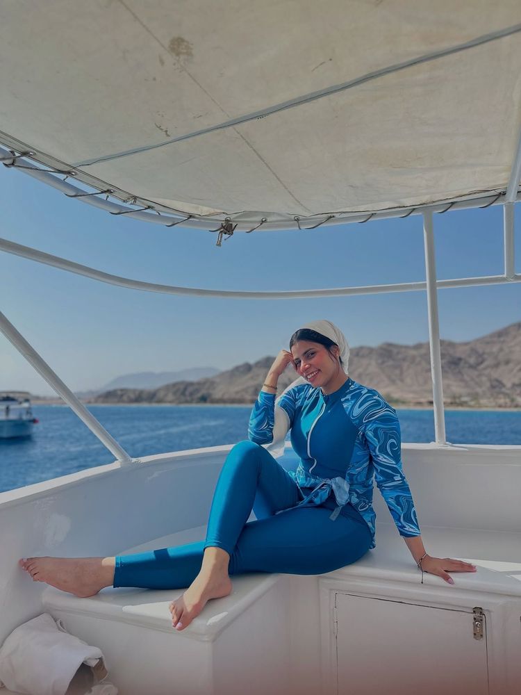 Woman in blue swim set and barefoot on a boat.