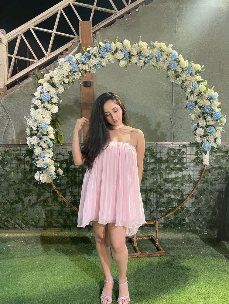 Girl in light pink strapless dress and strappy sandals in a floral setting.