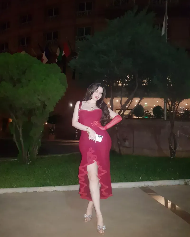 Woman in a red dress and clear heels in an elegant outdoor setting.