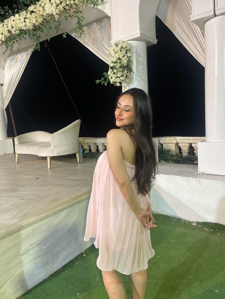 Girl in a blush pleated dress and open-toe sandals in an elegant setting