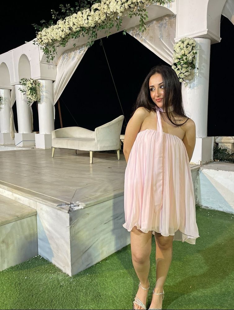 Girl in pastel pink mini dress and open-toe sandals in an elegant outdoor setting.