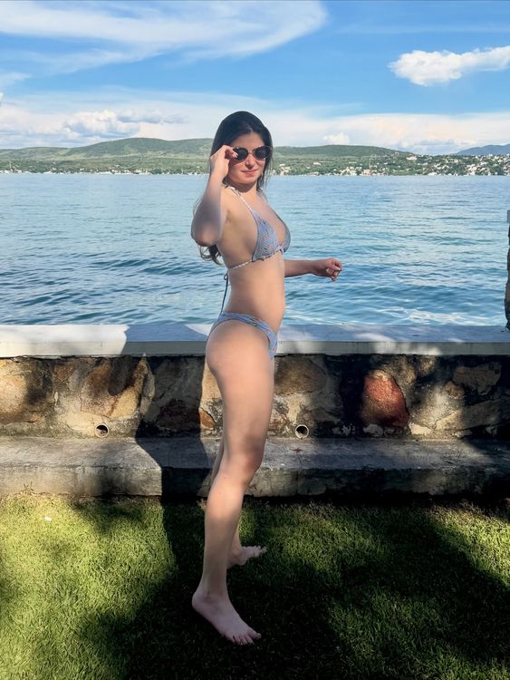 Girl in blue bikini and sunglasses by the lakeside