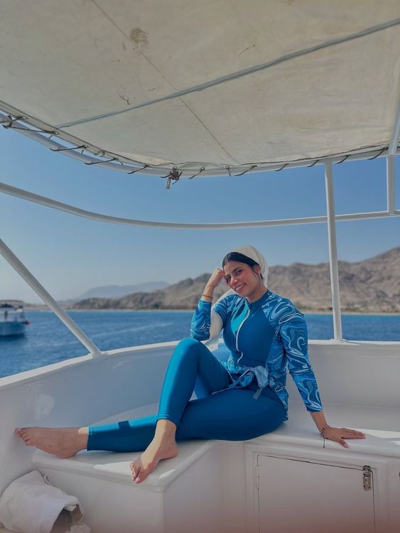 Woman in blue swim set and barefoot on a boat.