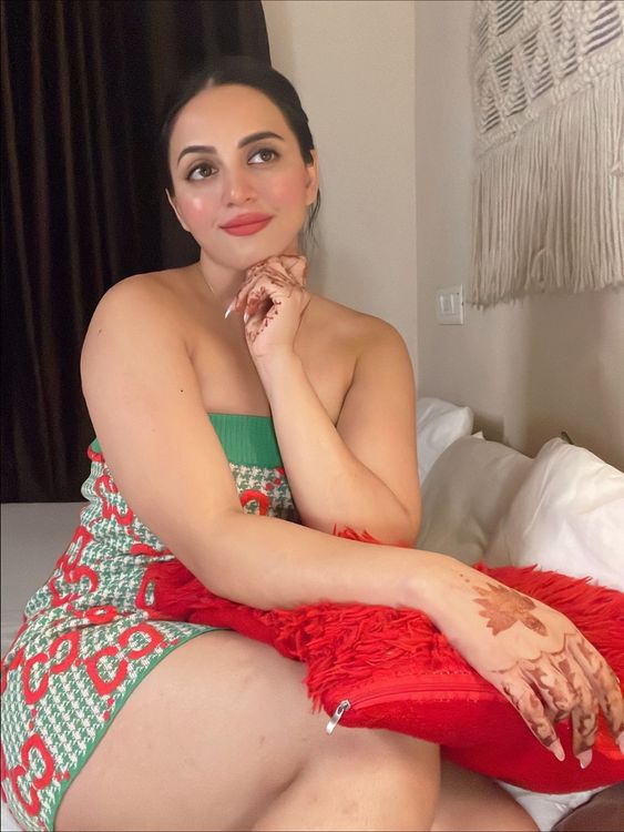 Woman in a colorful patterned mini dress and barefoot in a cozy indoor setting