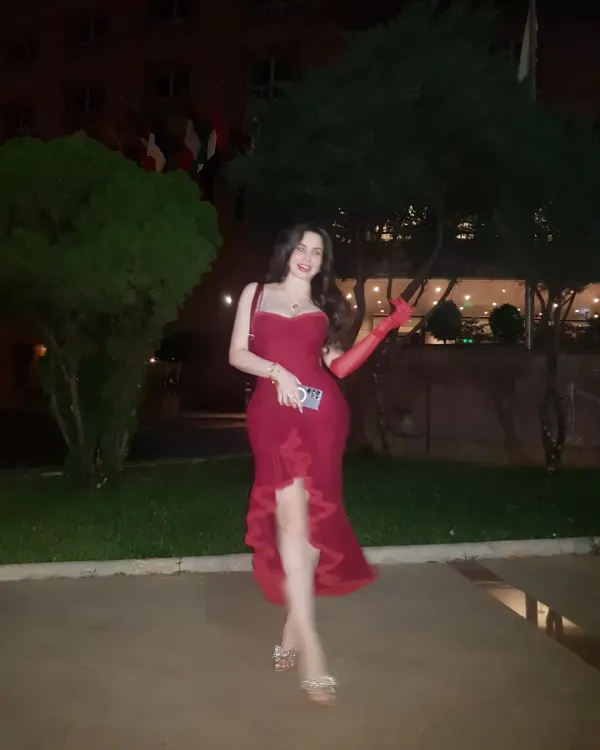 Woman in a red gown and silver heels in an outdoor setting.