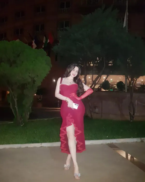 Woman in a red dress and clear heels in an elegant outdoor setting.