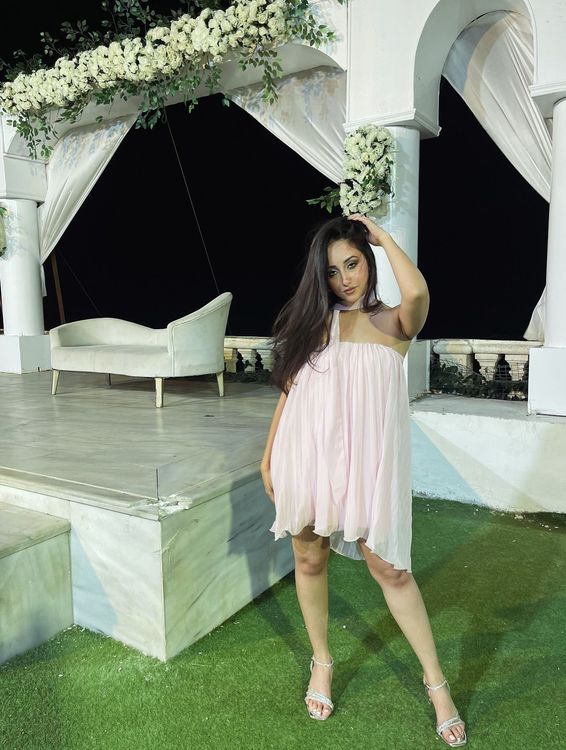 Girl in pink flowing dress and silver sandals in an elegant outdoor setting