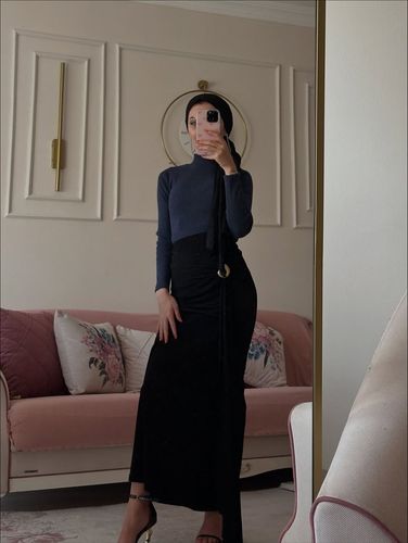 Woman in gray turtleneck and black maxi skirt in elegant setting