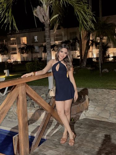 Woman in navy blue mini dress and brown heeled sandals in tropical setting