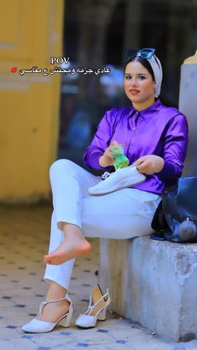 Girl in purple blouse and white trousers, barefoot in a sunny outdoor setting.
