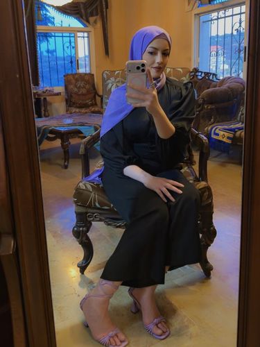 Girl in black dress and lavender strappy sandals in a cozy room