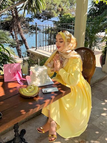 Woman in a yellow dress and open-toe sandals at a waterfront table