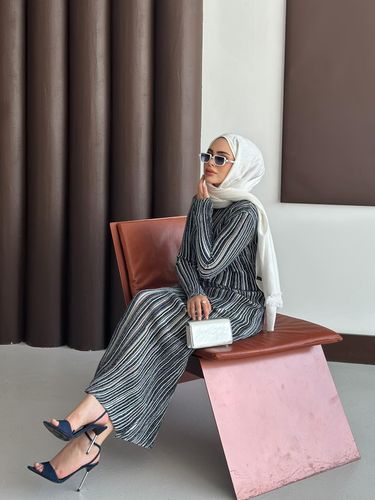 Woman in striped dress and high heels sitting in a modern setting