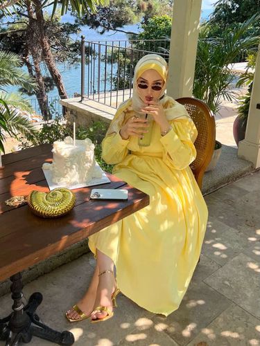 Woman in yellow dress and strappy sandals in outdoor setting with water view
