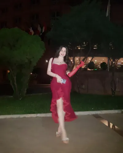 Woman in a red gown and silver heels in an outdoor setting.