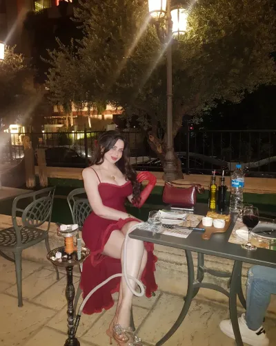 Woman in deep red dress and silver heels at outdoor dining setting